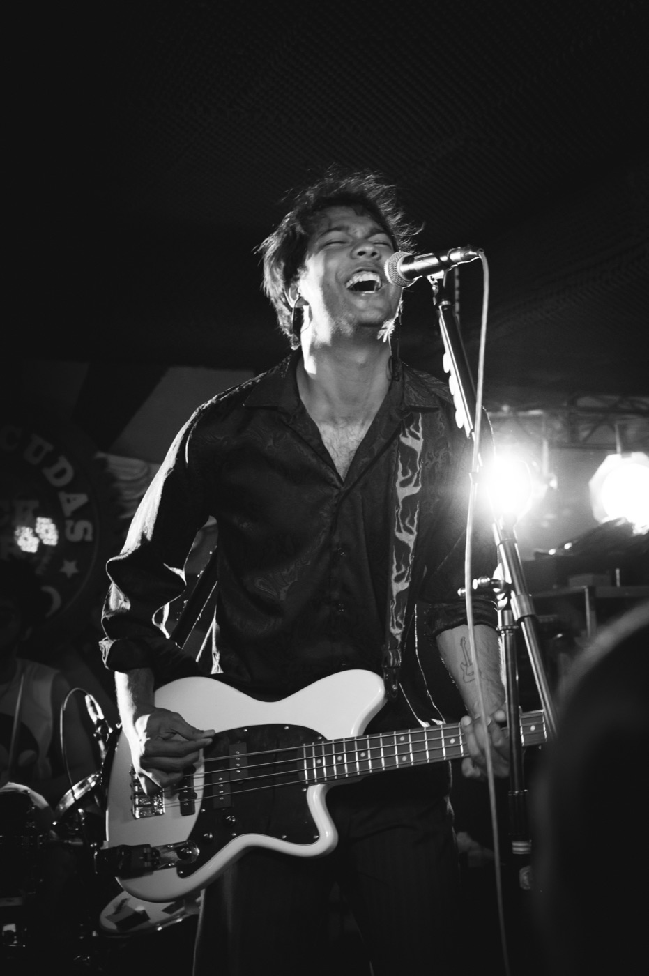 Black-and-white live shot: weyvir singing and playing bass under stage lights