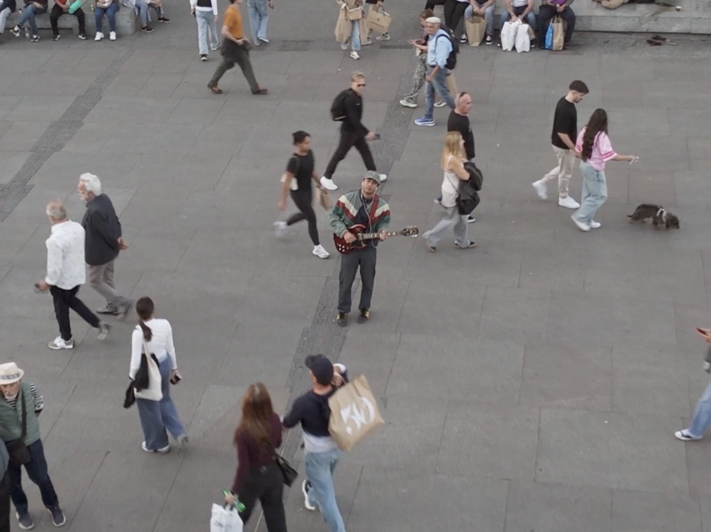 Overhead shot of weyvir busking with an electric guitar in a busy plaza, from the just gotta let u know video